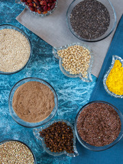 Superfoods in glassware on blue background. Bright colorful flat lay of healthy food products.