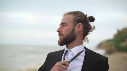 tired businessman in black suit loosening tie enjoying resting near seaside after busy day slomo closeup