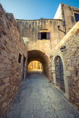Fototapeta na wymiar Old narrow street with stone arch at Atsipopoulo, Rethimno, Crete, Greece.