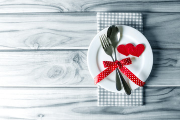 red heart shape with White empty plate with fork and spoon on wooden table for love dinner concept - Powered by Adobe
