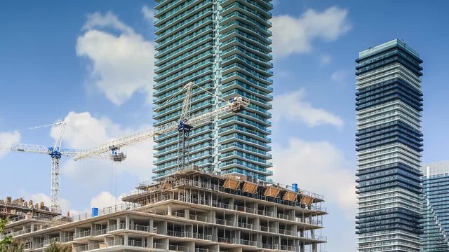 Timelapse of constraction site and residential high rise buildings with moving white clouds in blue sky, Toronto 