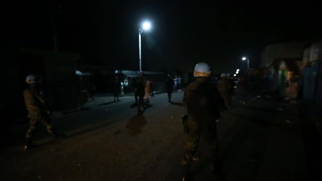 A party of UN soldiers make their way through dark streets at night