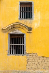 The old wooden window on yellow ancient brick wall