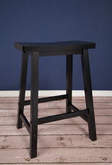 Saddle Seat Stool in a Room with a Wooden Floor and Blue Wall