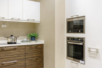 Modern kitchen furniture with contemporary kitchenware like hood, black induction stove, faucet and...