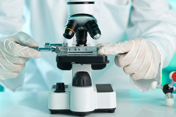 Research scientist working with specimen plate on microscope with molecule model