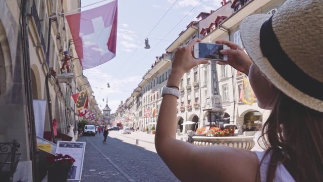 Tourist Woman Taking Photographs in Bern, Switzerland. SLOW MOTION 240 fps. Traveller making a Picture of Kramgasse with a Smartphone in the Old Town of Bern in summer. Travel Europe concept 