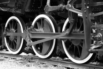 Closeup of old locomotive train wheels, three white, black and white image