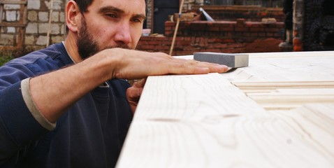 Мужчина проверяет качество работы по дереву © svetlarud