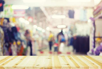 Blurred image of retail store in shopping mall montage with wood table for background.