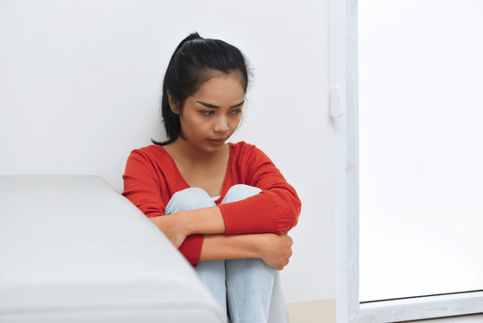 Portrait of sad asian woman sitting and hugging knee