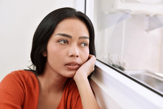 Portrait of asian woman daydreaming and looking through a window