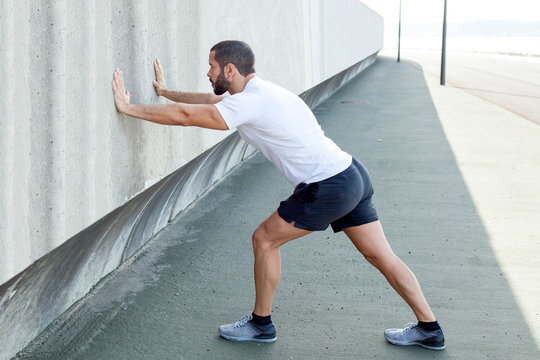 Strong Man Stretching Calf And Leaning On Wall