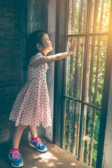 Asian girl with beautiful dress looking at the sunrise standing near the window.