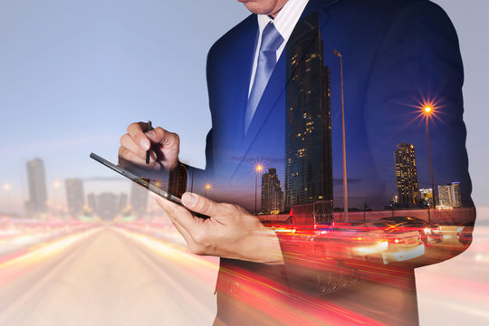 Double exposure of businessman hand hold tablet, light trails on the street and urban at dusk, night as business, technology and communication concept.