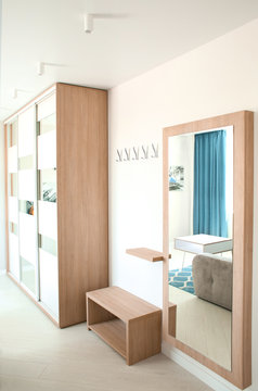 Interior of light modern living room with wardrobe and mirror