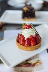 Strawberry tart topping with cream, eatable gold paper and chocolate sticks at the cafe in Dubai. 