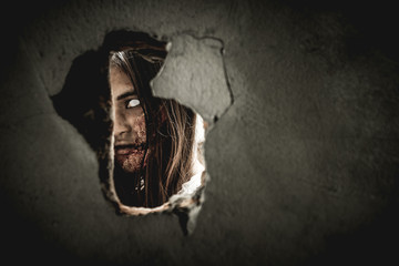 Woman in Halloween makeup looking through hole
