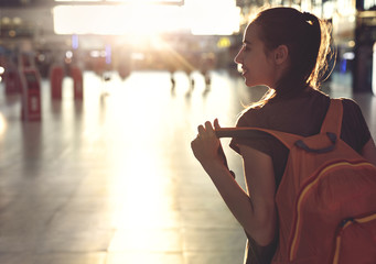 young woman in the hall of the airport terminal with small backpack as a hand luggage. silhouette...