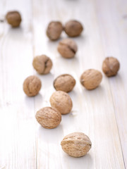 Walnuts on white wooden background.