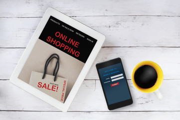Online shopping website on computer tablet and mobile banking on smartphone with cup of coffee on table