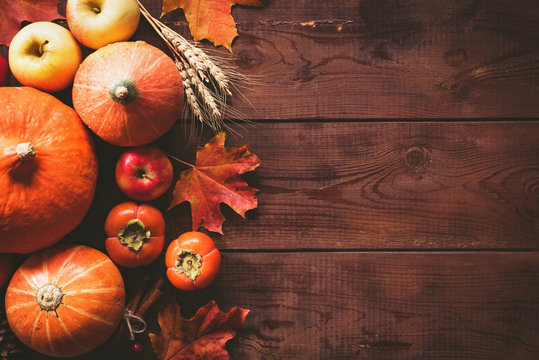 Thanksgiving background with pumpkins, apples and fallen leaves on wooden table