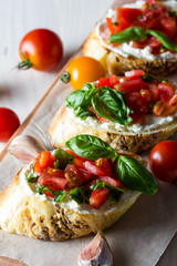 Tomato and cheese fresh made bruschetta. Italian tapas, antipasti with vegetables, herbs and oil on grilled ciabatta and baguette bread.