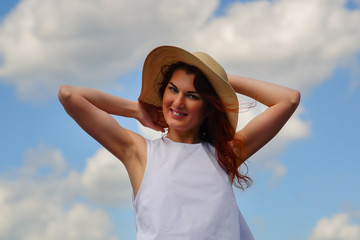 Happy female in white dress and hat, blue sky and clouds on background