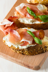 Italian tomato, prosciutto, jamon, ham and cheese bruschetta. Tapas, antipasti with chopped vegetables, herbs and oil on grilled ciabatta and baguette bread.