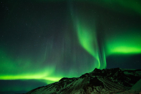 northern lights appear over mountain.