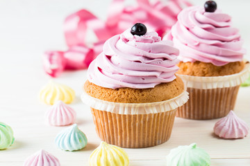 Closeup of cupcakes with vanilla, berries, pink and white cream, chocolate and sprinkles on wooden background. Selective focus. Sweet dessert tasty food concept muffin.