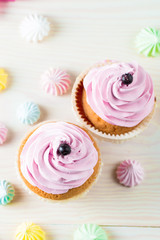 Closeup of cupcakes with vanilla, berries, pink and white cream, chocolate and sprinkles on wooden background. Selective focus. Sweet dessert tasty food concept muffin.