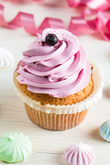 Closeup of cupcakes with vanilla, berries, pink and white cream, chocolate and sprinkles on wooden background. Selective focus. Sweet dessert tasty food concept muffin.