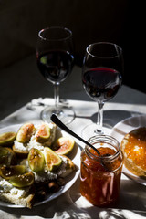 two glasses of red wine with sandwiches with red caviar and bruschettes with cheese and figs. in the kitchen at the window