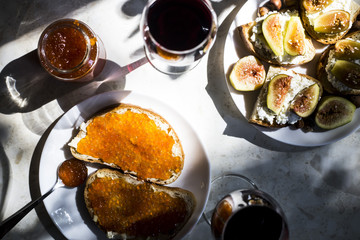 two glasses of red wine with sandwiches with red caviar and bruschettes with cheese and figs. in the kitchen