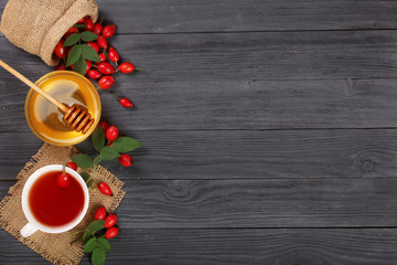 tea with rose hips and honey on a black wooden background with copy space for your text. Top view