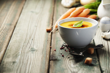 Vegetable cream soup in bowl over old wooden background