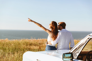 Back view of Young lovely couple standing near the retro car