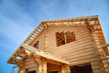 Structure of a new wooden house under construction on blue sky background