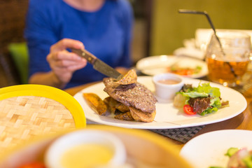 Girl eating meat with salad in a restaurant