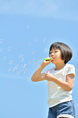 シャボン玉遊びをする女の子(青空)