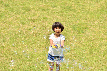 芝生広場でシャボン玉遊びをする女の子
