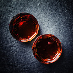 Scotch whiskey in a glass on a black stone background, top view
