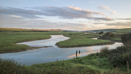 Beautiful dawn landscape over English countryside with river slowly flowing through fields