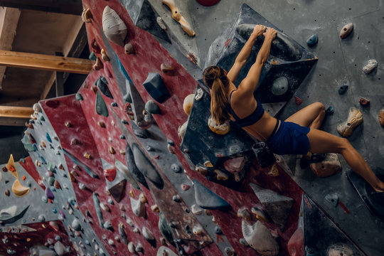 Free climber female bouldering indoors.