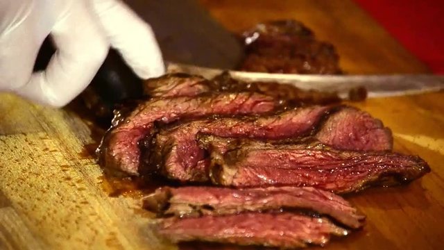 Slicing grilled beef steak meat.