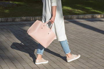 Young woman with pink handbag is walking on the street. Lifestyle, casual street style