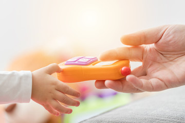 Father's and baby's hand holding toy phone.
