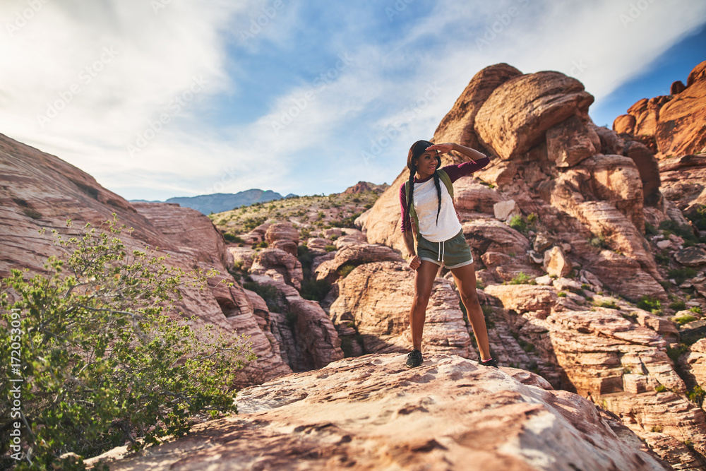 Wall mural athletic african american woman standing on cliff edge at red rock canyon park