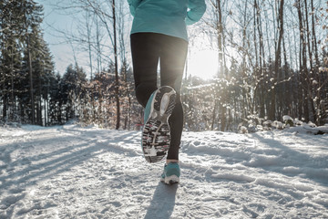 Woman Running at snowly winter under sunlight.